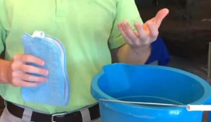 Man with bucket of water and absorbent cloth ready to wipe down fireplace wall.