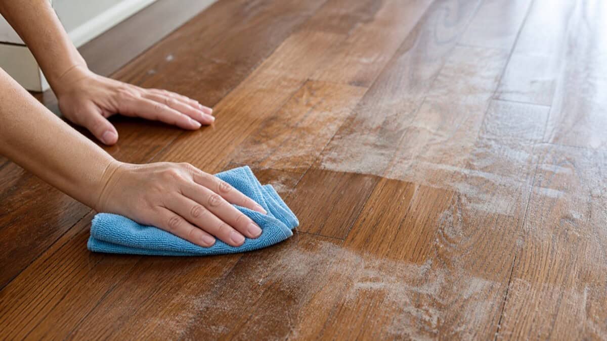 Using a barely damp microfiber cloth to remove white residue from a hardwood floor